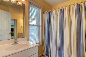 een badkamer met een wastafel, een spiegel en een raam bij Barefoot Bungalow in Surf City