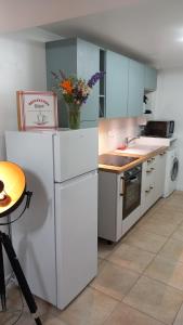una cocina con electrodomésticos blancos y un jarrón de flores en Gîte L'Instant Présent, en Messeix