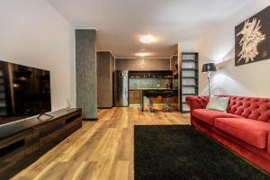 sala de estar con sofá rojo y suelo de madera en Tampa Gardens Zen Apartment - Adults Only en Braşov