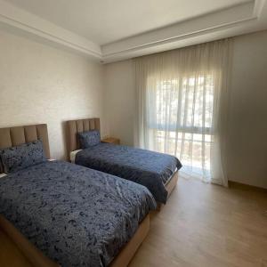 塔哈佐特Taghazout Paradise - Duplex Confort - Vue mer piscine - Agadir的有两张床和一扇窗户的卧室 更多15张照片