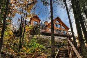 a log cabin in the woods with a staircase at Chalet Le Montcalm in Saint Adolphe D'Howard