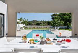 a table with food and wine glasses next to a pool at Aurum Villas in Ialyssos