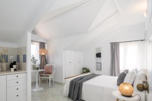 a white bedroom with a white bed and a chair at Eraora Lofts & Apartments Kefalonia in Lakithra