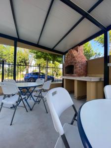 a patio with white chairs and a table and a brick oven at Casa Andreea in Eforie Sud