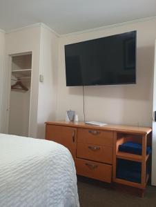 a bedroom with a bed and a dresser with a flat screen tv at The Ashley in Saranac Lake