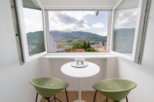 ein weißer Tisch mit zwei grünen Stühlen vor einem Fenster in der Unterkunft Old Town Heaven 3-bedroom apartment with balcony in Sarajevo