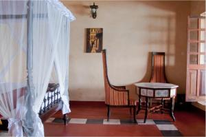 Zimmer mit 2 Stühlen, einem Tisch und einem Fenster in der Unterkunft Mizingani Seafront Hotel in Zanzibar City