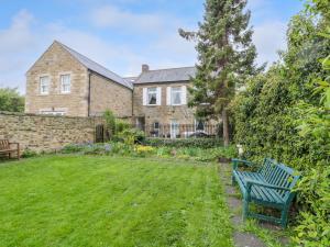 eine blaue Bank im Garten eines Hauses in der Unterkunft White Swan Cottage in Alnwick