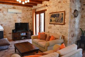 a living room with a couch and a tv at Julieta Stone Villa in Andip&aacute;ta Er&iacute;sou
