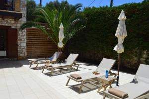 a group of lounge chairs and umbrellas on a patio at Julieta Stone Villa in Andip&aacute;ta Er&iacute;sou