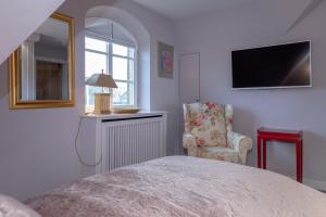 Un dormitorio con una cama y una silla y un televisor. en Weetstich, en Archsum