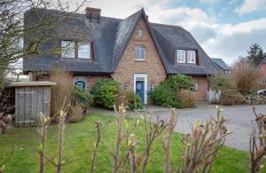 una casa de ladrillo rojo con techo negro en Weetstich, en Archsum