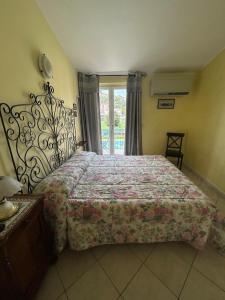 a bedroom with a bed with a floral bedspread and a window at Appartamento Vista mare con Piscina Cala di Sole in Imperia