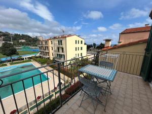 a balcony with a table and chairs next to a pool at Appartamento Vista mare con Piscina Cala di Sole in Imperia