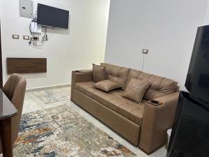 a living room with a brown couch and a tv at Blue Bay Village- Private Chalet in Marsa Matruh