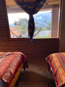 a window in a room with two beds and a view at Loma Wasi Alojamiento Rural Indígena en Cotacachi in Cotacachi