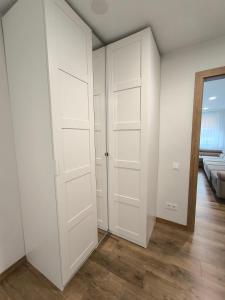 an empty room with white doors and a couch at Tukas Apartment in Marijampolė