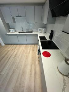 a kitchen with white cabinets and a wooden floor at KM Granton Apartment in Edinburgh +11 photos