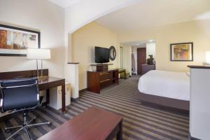 a hotel room with a bed and a desk and a tv at Best Western Suites near Opryland in Nashville