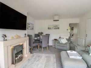 a living room with a fireplace and a tv at Benllech Bay Cottage in Benllech
