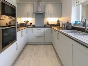 a kitchen with white cabinets and a wooden floor at Benllech Bay Cottage in Benllech