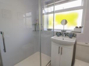 a white bathroom with a sink and a shower at Benllech Bay Cottage in Benllech +12 photos