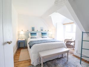 una camera da letto bianca con un letto con cuscini blu di Ivy Cottage a Harlech