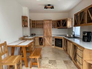 a kitchen with wooden cabinets and a table and chairs at Casuta Mosului in Ocna Şugatag