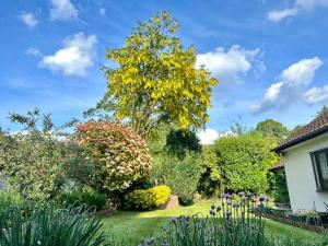a garden with flowers and trees and a house at Linden Suite in Goring