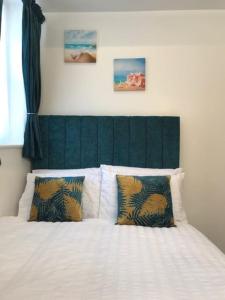 a bedroom with a white bed with a green headboard at On the Beach Retreat in Bournemouth