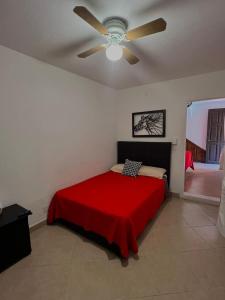 een slaapkamer met een rood bed en een plafondventilator bij Casa 86 in San Miguel de Allende