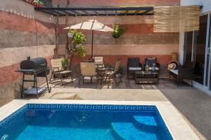 a swimming pool with chairs and a table and an umbrella at Increible Casa Céntrica con Alberca Climatizada in Oaxaca City