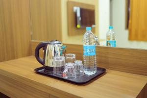 a tea kettle and glasses of water on a tray at JKInn in Vellore