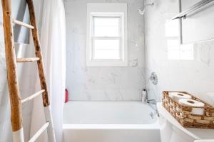 a white bathroom with a white tub and a window at The Blue Sapphire 2BR 2 King beds & ample backyard in Bridgeport +59 photos