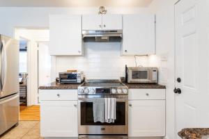 a kitchen with white cabinets and a stove top oven at The Blue Sapphire 2BR 2 King beds & ample backyard in Bridgeport