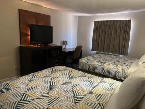 a hotel room with two beds and a flat screen tv at Economy Suites - Tulsa Airport in Tulsa