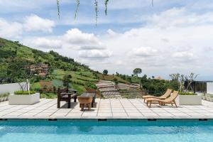 ein Pool mit Stühlen und ein Tisch neben einem Hügel in der Unterkunft Jaden Hill Mountain City View Villa 8 bedrooms with a private heated swimming pool and a movie room in Bengkok