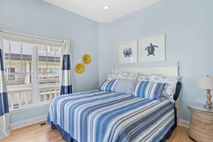 a bedroom with a bed with a striped comforter and a window at Topsail Treasure's - Oceanfront Luxury Spa Pool in North Topsail Beach +48 photos