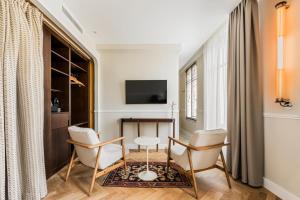 a living room with a table and chairs and a television at Hôtel Chamar in Paris