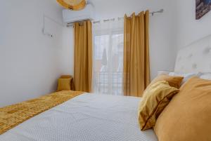 a bedroom with a bed with yellow curtains and a window at Chez Oasis Lagos - Charming Central by the Beach in Lagos