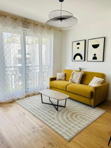 ein Wohnzimmer mit einem gelben Sofa und einem Couchtisch in der Unterkunft Bel appartement à 5 mn de Paris très proche Métro 13 et 14 in Saint-Ouen