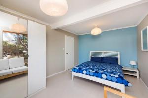 Dormitorio azul con cama y sofá en Seaclusion Cottage - Modern renovated beach house, en Guilderton