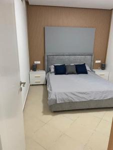 a bedroom with a bed with blue pillows and two night stands at 2 Bedroom flat Shengjin in Margjonaj