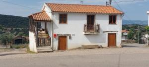a white house with brown doors on a street at Casa do Soto in Milhão