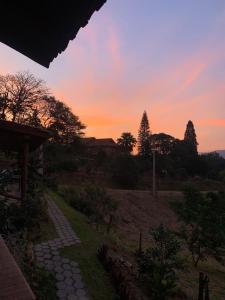 a sunset over a garden with a stone path at Chalé Sol da Montanha em Termas do Gravatal - SC in Gravatal