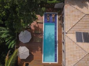 a swimming pool with two umbrellas next to a house at Villa Maritaca Condomínio de 4 Casas de Locação por Temporada de Alto Padrão com SPA in Arraial d'Ajuda