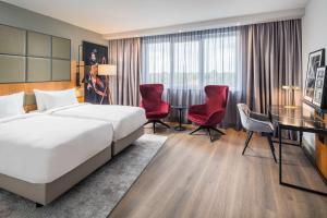 a hotel room with a bed and a desk and chairs at Radisson Blu Hotel, Hamburg Airport in Hamburg