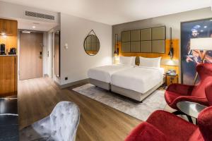 a bedroom with a white bed and red chairs at Radisson Blu Hotel, Hamburg Airport in Hamburg