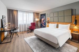 a hotel room with a large white bed and a desk at Radisson Blu Hotel, Hamburg Airport in Hamburg