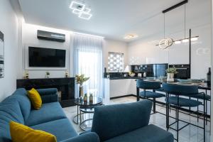 a living room with a blue couch and a kitchen at Laskaris Luxury Apartment in Kalamata